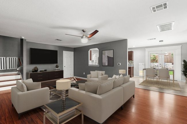 Living area featuring ceiling fan, wood finished floors, and stairway | Image 4