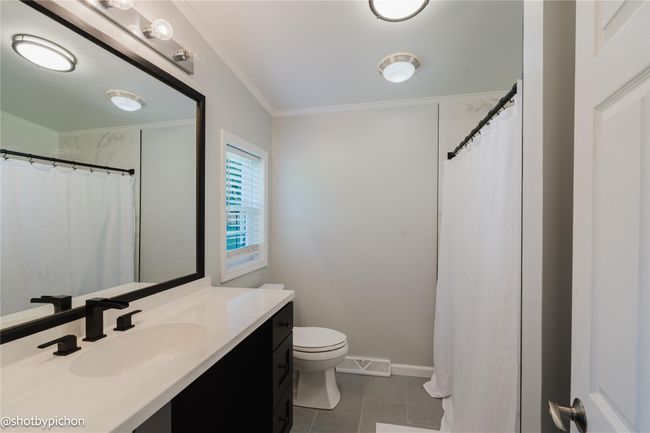 Full bathroom featuring vanity, tile patterned floors, ornamental molding, and curtained shower | Image 14