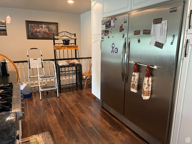 Kitchen featuring freestanding refrigerator, dark wood finished floors, recessed lighting, dark countertops, and white cabinetry | Image 6