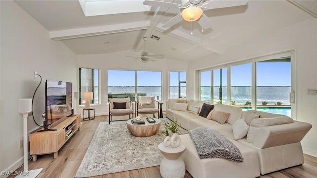 Living room with light wood finished floors, a ceiling fan, and a skylight | Image 13