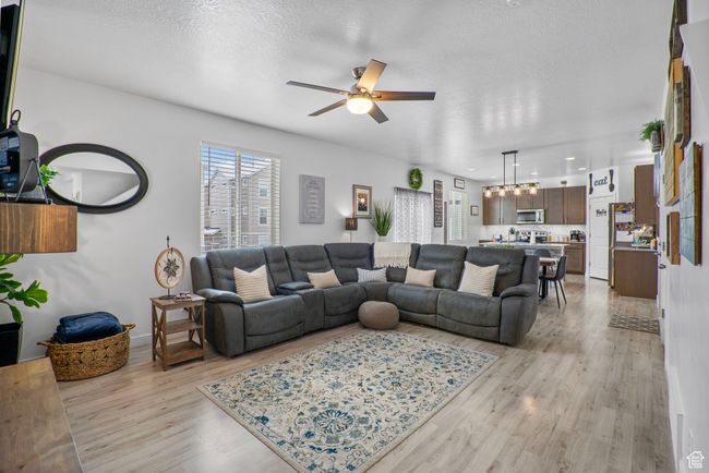 Living room featuring a textured ceiling, ceiling fan with notable chandelier, light wood-style floors, baseboards, and recessed lighting | Image 28