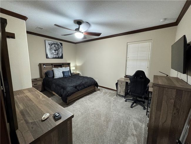 Carpeted bedroom with ornamental molding, a desk, ceiling fan, and a textured ceiling | Image 16