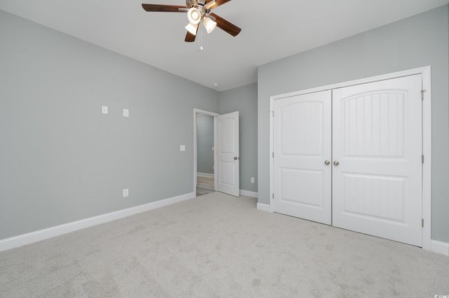 Unfurnished bedroom featuring ceiling fan, a closet, and light carpet | Image 10