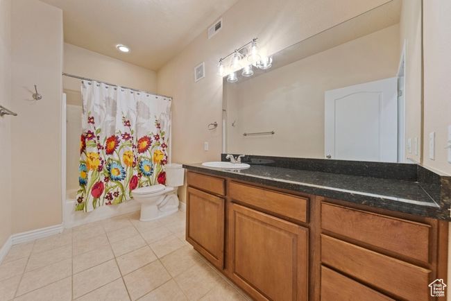 Full bathroom with toilet, tile patterned flooring, vanity, shower / bathtub combination with curtain, and baseboards | Image 7