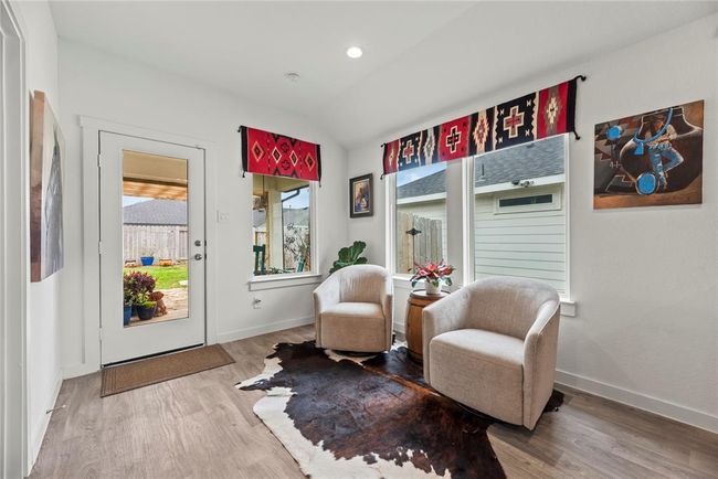 The breakfast area is bright and inviting, featuring a door with a large window that fills the space with natural light. In addition to the door, there are three other windows that offer views of the backyard, enhancing the open, airy feel of the room. The natural wood-colored LVP flooring flows throughout, adding warmth and a touch of elegance. The door conveniently leads to the backyard, making it easy to step outside and enjoy the outdoor space, perfect for meals or relaxing in the fresh air. | Image 9