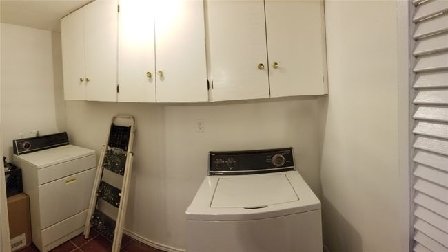 Clothes washing area featuring cabinet space, washer and dryer, and dark tile patterned floors | Image 17