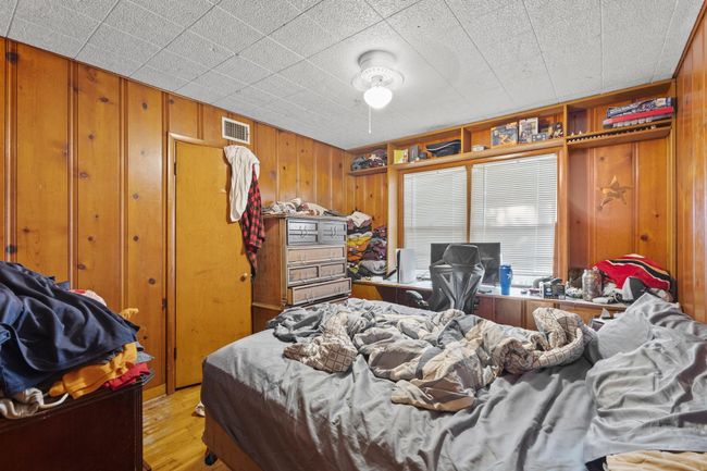 Bedroom featuring wood walls, light wood-type flooring, and an office area | Image 11