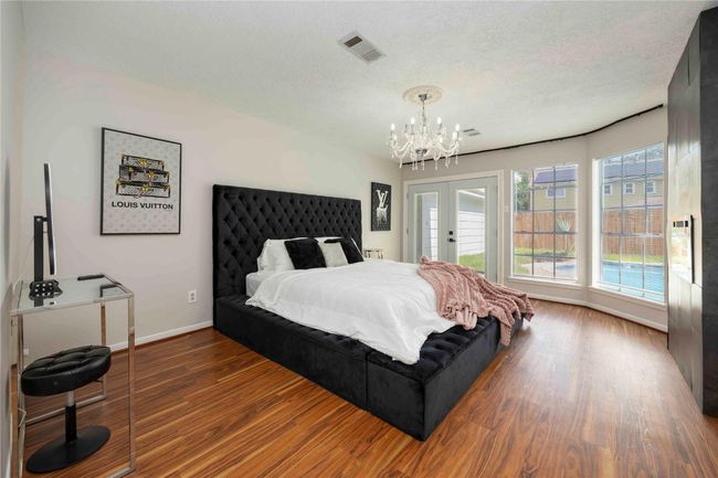 Well-lit and spacious master bedroom on the first floor, offering a clear view of the backyard pool. | Image 25