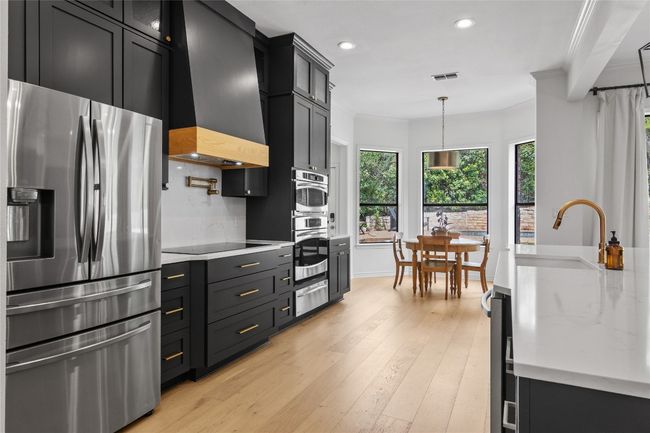 Kitchen featuring a sink, wall chimney range hood, recessed lighting, crown molding, and appliances with stainless steel finishes | Image 14