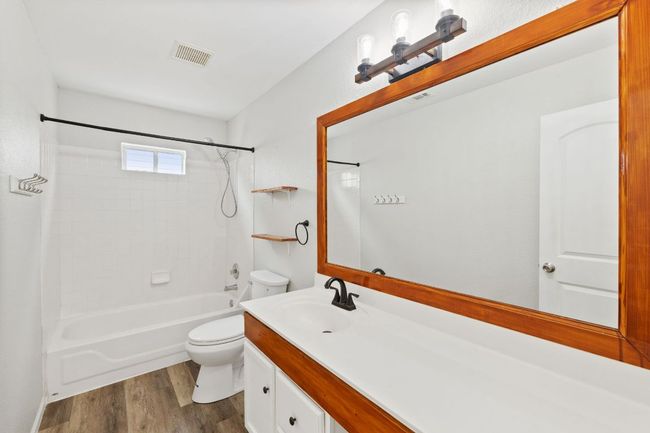 Bathroom with toilet, vanity, bathtub / shower combination, and wood finished floors | Image 27