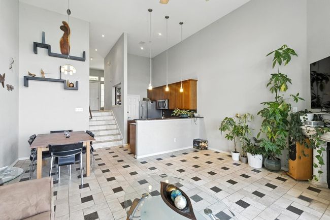 Kitchen featuring a high ceiling, appliances with stainless steel finishes, light tile patterned floors, pendant lighting, and brown cabinetry | Image 10