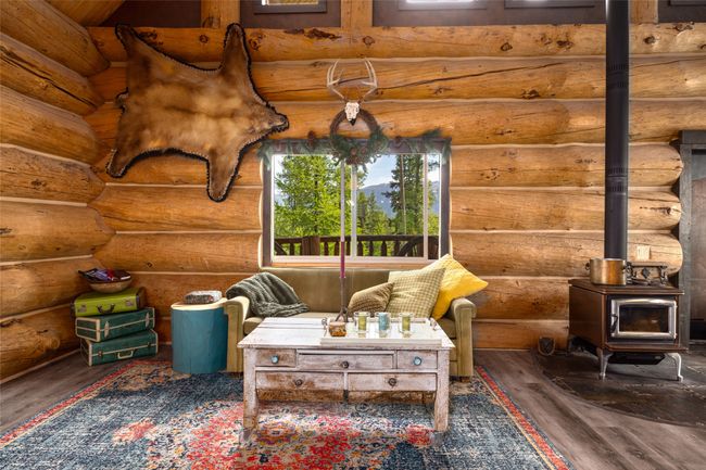 Living room featuring a wood stove, wood finished floors, and rustic walls | Image 8