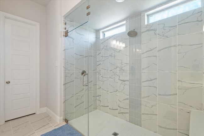 Bathroom featuring tiled shower, marble finish flooring, and baseboards | Image 24