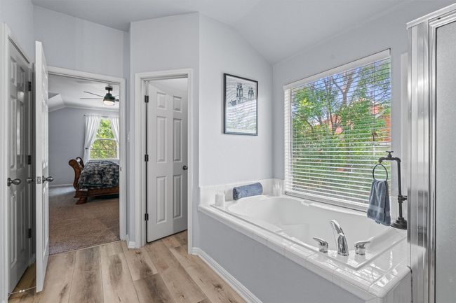 Bathroom with lofted ceiling, a bath, wood finished floors, and a ceiling fan | Image 27