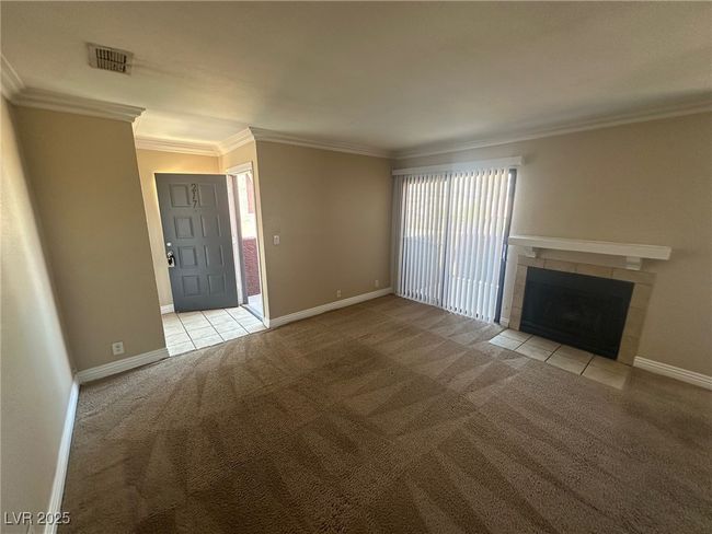 Unfurnished living room featuring a tiled fireplace, visible vents, carpet floors, and crown molding | Image 5