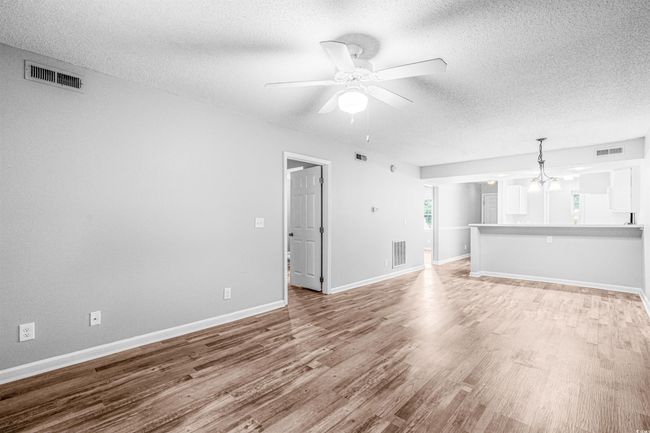Unfurnished living room featuring a textured ceiling, light wood-type flooring, a ceiling fan, and a chandelier | Image 13