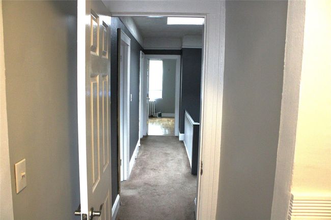 Hallway with carpet floors and radiator heating unit | Image 18