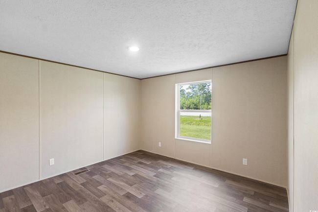 Empty room with wood finished floors, a textured ceiling, and recessed lighting | Image 20