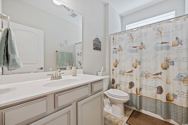 Full bathroom featuring double vanity, toilet, tile patterned flooring, and curtained shower | Image 25