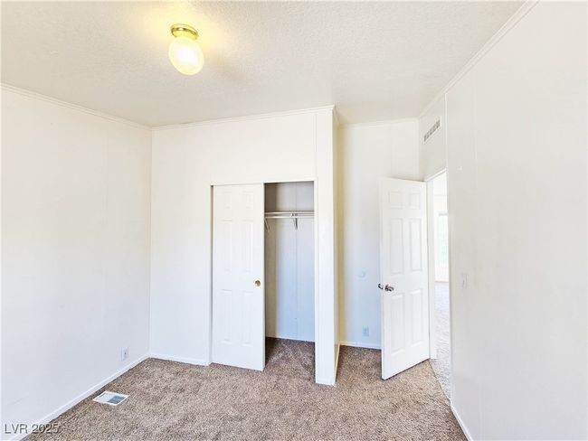 Unfurnished bedroom with a closet, visible vents, carpet, ornamental molding, and a textured ceiling | Image 19
