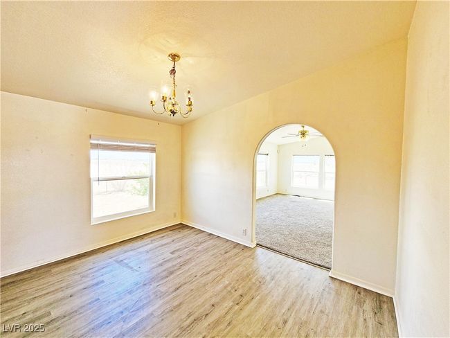 Spare room featuring baseboards, wood finished floors, a notable chandelier, and arched walkways | Image 11