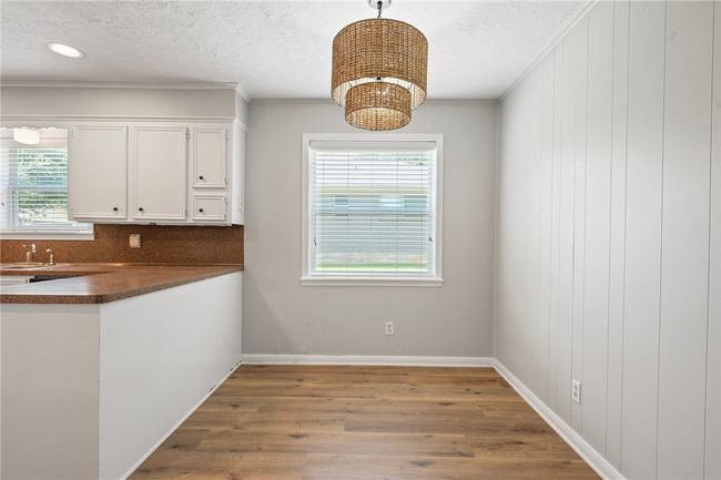 Unfurnished dining area featuring wood finished floors, crown molding, baseboards, a textured ceiling, and a chandelier | Image 7