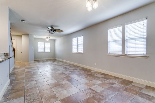 Empty room with a ceiling fan and light tile patterned floors | Image 8