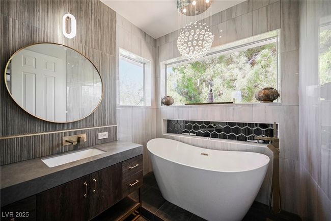 Master Bathroom with a soaking tub, vanity, a notable chandelier, and tile walls | Image 56