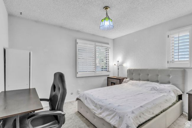 Bedroom featuring a textured ceiling, light colored carpet, and a desk | Image 12