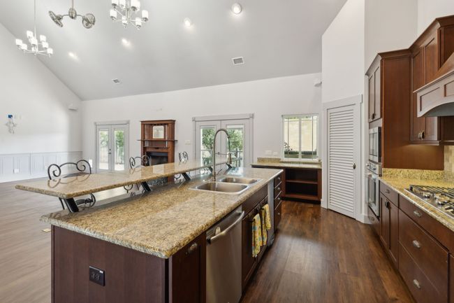 Kitchen featuring stainless steel appliances, plenty of natural light, sink, a kitchen island with sink, and high vaulted ceiling | Image 9
