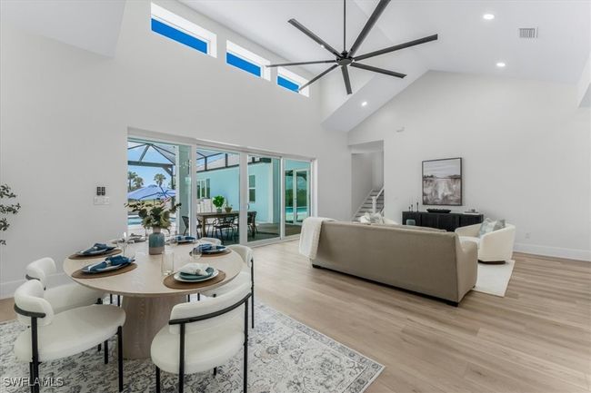 Dining area with a towering ceiling, healthy amount of natural light, light wood-style floors, stairs, and a ceiling fan | Image 24