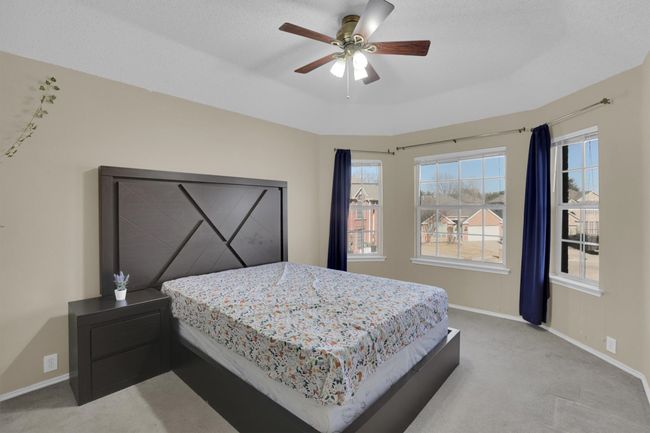 Bedroom with light carpet, ceiling fan, a tray ceiling, and baseboards | Image 32