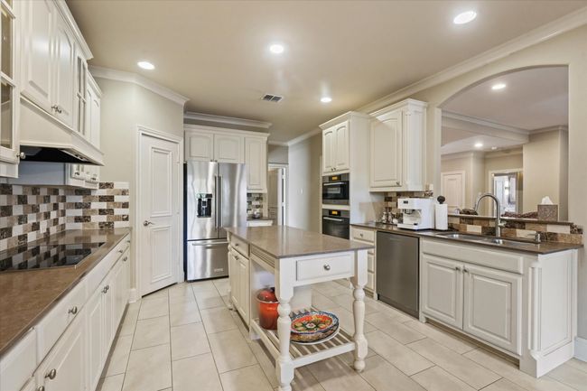 Kitchen with appliances with stainless steel finishes, a sink, arched walkways, decorative backsplash, and recessed lighting | Image 15