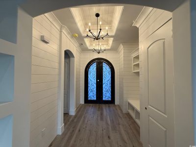 Doorway to outside featuring wood walls, french doors, a raised ceiling, hardwood / wood-style flooring, and a chandelier | Image 3