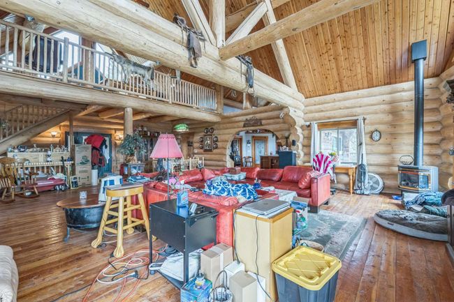 Living area with a wood stove, high vaulted ceiling, log walls, hardwood / wood-style flooring, and wooden ceiling with exposed beams | Image 23