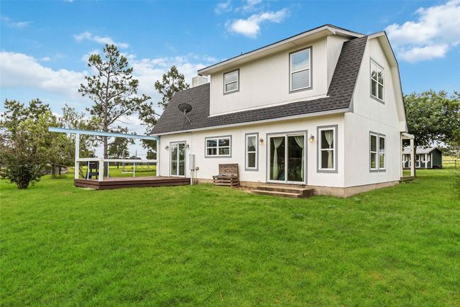 Rear view of property with a shingled roof, a deck, a lawn, and entry steps | Image 31