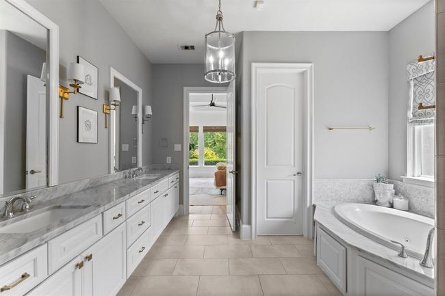 The primary bathroom is a spa-like sanctuary with dual vanities, a separate walk-in shower, and a garden tub. | Image 19