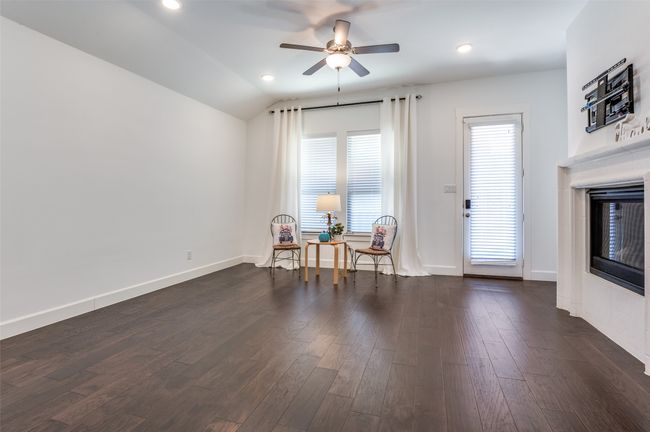 The living room features elegant dark wood-style flooring, a glass-enclosed fireplace, a ceiling fan, and baseboards. | Image 11