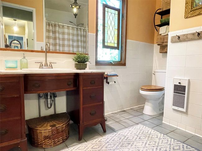 Full bathroom featuring wainscoting, tile walls, heating unit, tile patterned floors, and vanity | Image 19