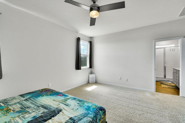 Bedroom featuring carpet flooring, baseboards, a ceiling fan, and ensuite bathroom | Image 17