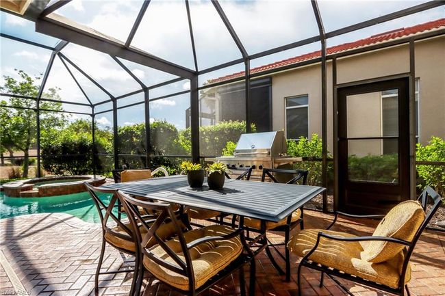 View of patio / terrace with glass enclosure, area for grilling, a pool with connected hot tub, and outdoor dining space | Image 23