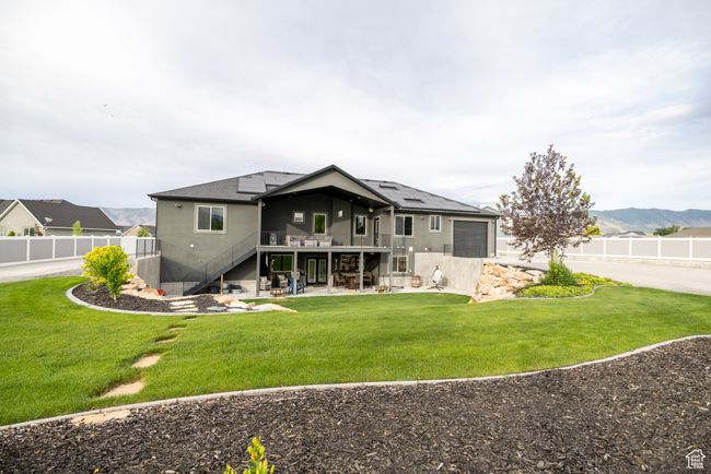 Rear view of house with stairs, roof mounted solar panels, a patio, a deck with mountain view, and an attached garage | Image 77