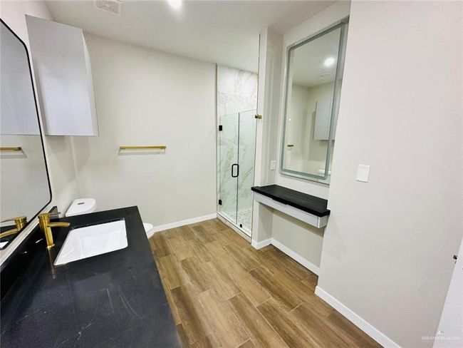 Full bathroom with a marble finish shower, wood finished floors, baseboards, and vanity | Image 7