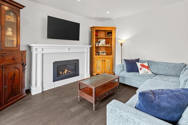 Living room featuring dark wood-style floors, a fireplace, and recessed lighting | Image 13