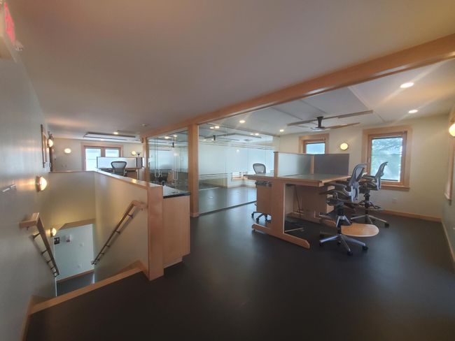 Upper level view of all. There are work stations on either end and a private glass enclosed office in the center. | Image 19