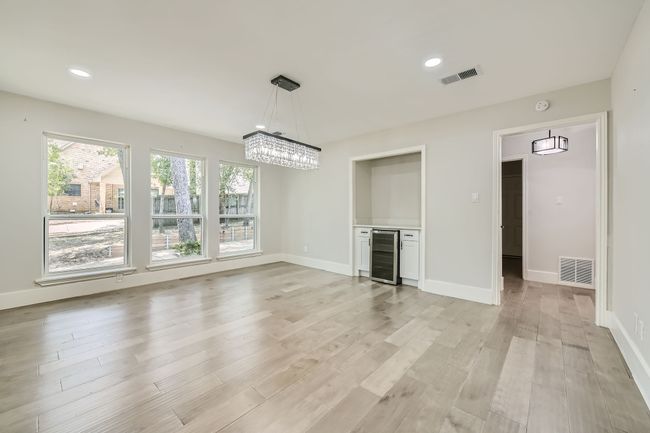 Unfurnished living room with baseboards, visible vents, light wood-type flooring, and wine cooler | Image 14