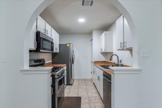Kitchen featuring a sink, white cabinets, visible vents, and stainless steel appliances | Image 8