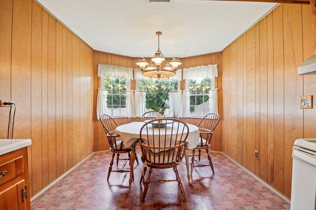 Dining room featuring wooden walls, a chandelier, and brick patterned floors | Image 10