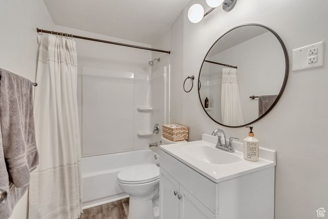 Full bath featuring vanity, shower / tub combo with curtain, and wood finished floors | Image 24