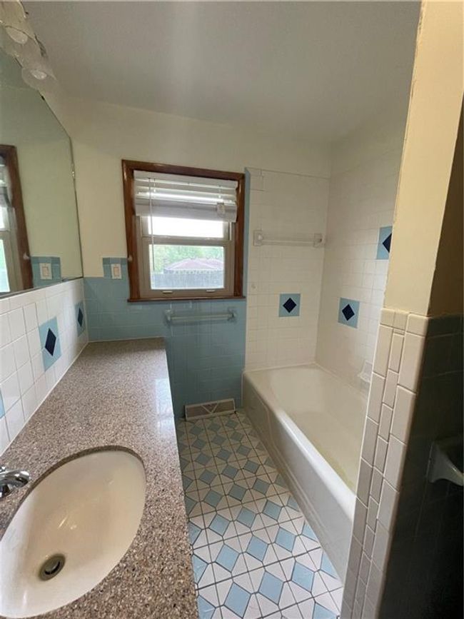 Bathroom featuring tile walls, a sink, a bathing tub, a wainscoted wall, and tile patterned flooring | Image 21